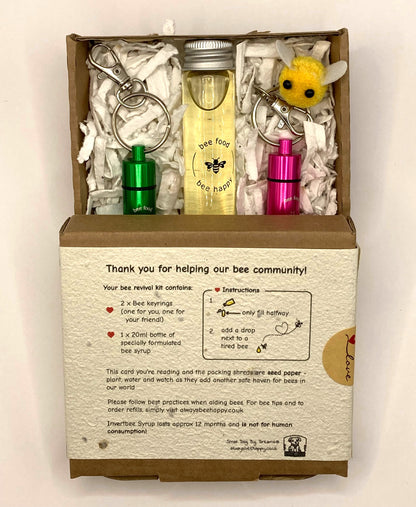 Showing bee revival kit box, opened showing the contents, consisting of glass bottle with 20ml Inveråtbee syrup, two bee revival keyrings, seed paper packing and a cute little fabric bee.