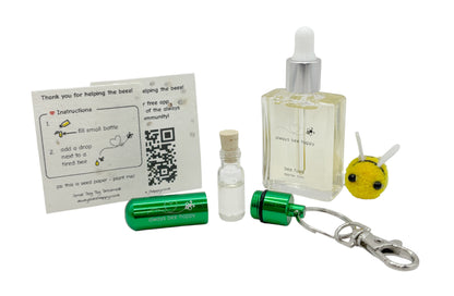 Bee revival kit including a 15ml bottle for top-ups, green aluminium keychain with inner glass vial and premium cork, and instruction card on seed paper. And a fluffy bee of course.