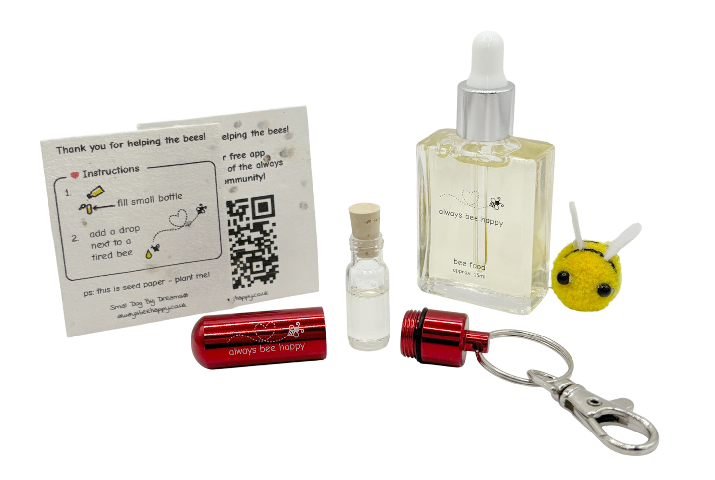 Bee revival kit including a 15ml bottle for top-ups, red aluminium keychain with inner glass vial and premium cork, and instruction card on seed paper. And a fluffy bee of course.