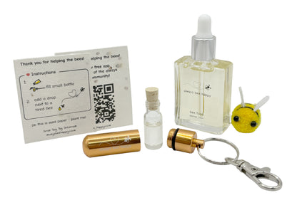 Bee revival kit including a 15ml bottle for top-ups, rose-gold aluminium keychain with inner glass vial and premium cork, and instruction card on seed paper. And a fluffy bee of course.